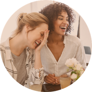 Three women laughing and enjoying drinks together at a café.